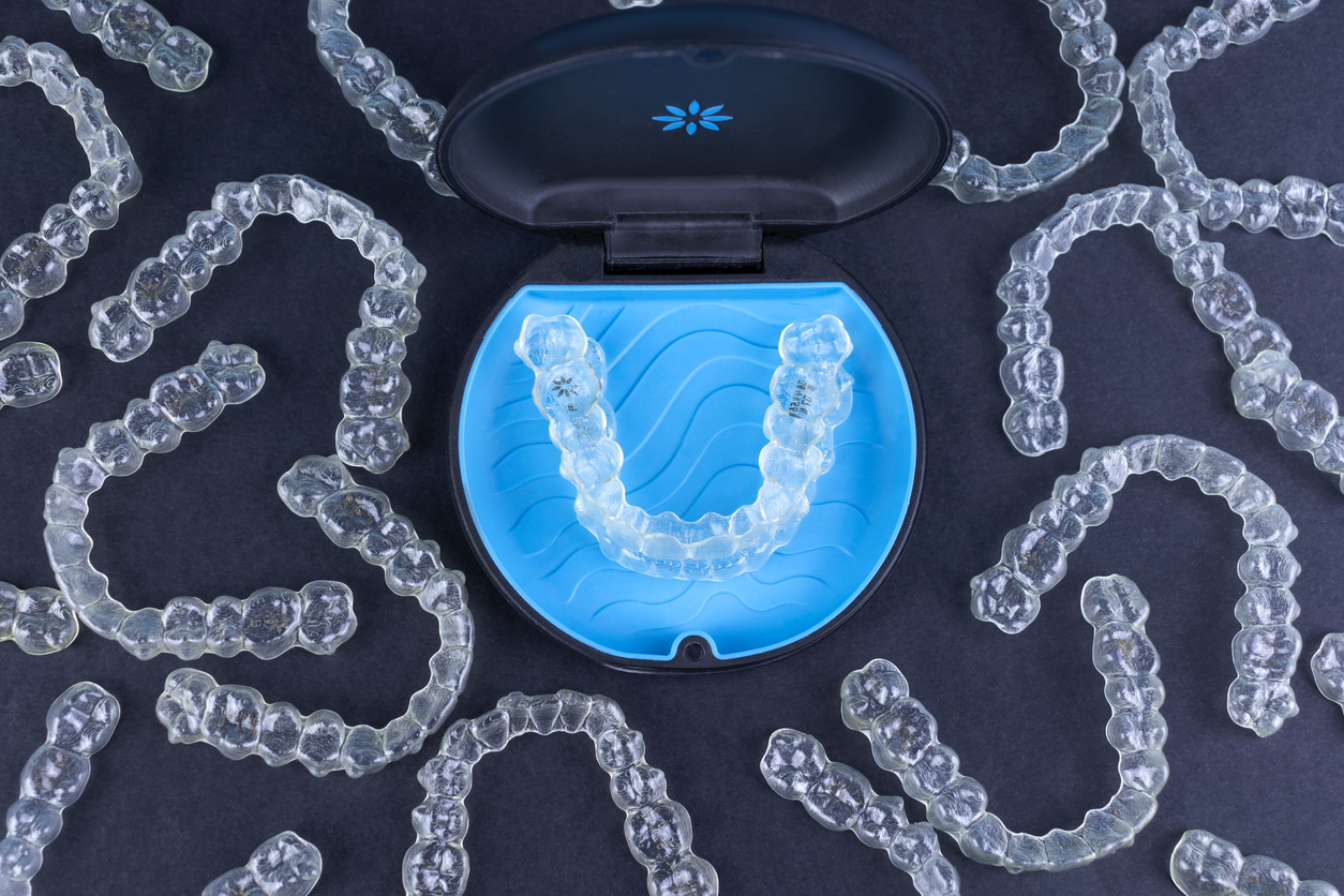 Plastic case with invisible transparent orthodontic retainers invisalign on black background. Aligner brackets or braces dental container