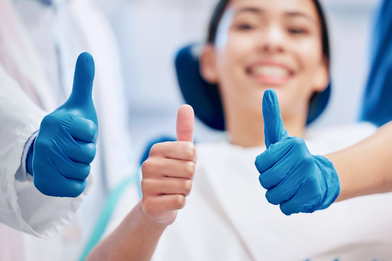 Shot of a young woman giving the thumbs up with her dentist