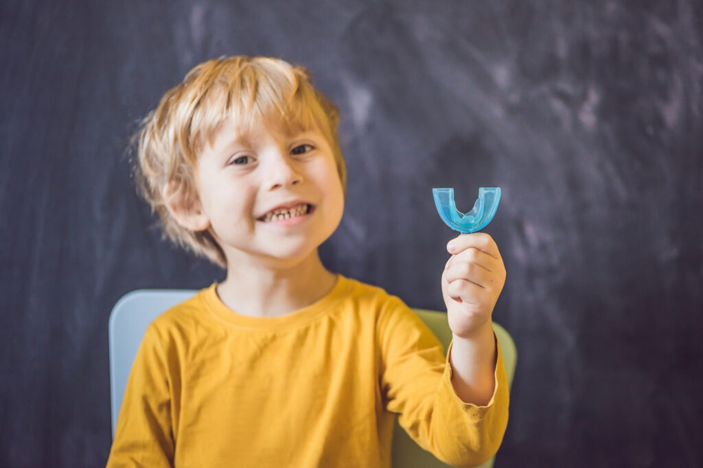 Three-year old boy shows myofunctional trainer. Helps equalize the growing teeth and correct bite, develop mouth breathing habit. Corrects the position of the tongue