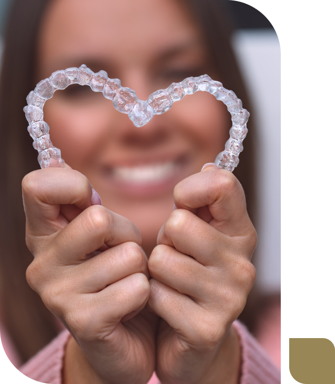 smiling woman holding two Invisalign aligners