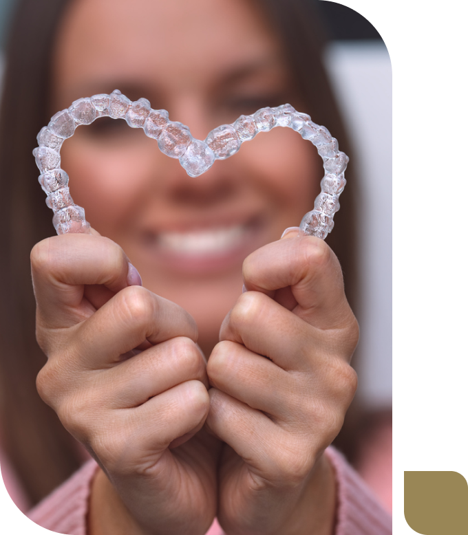 smiling woman holding two Invisalign aligners