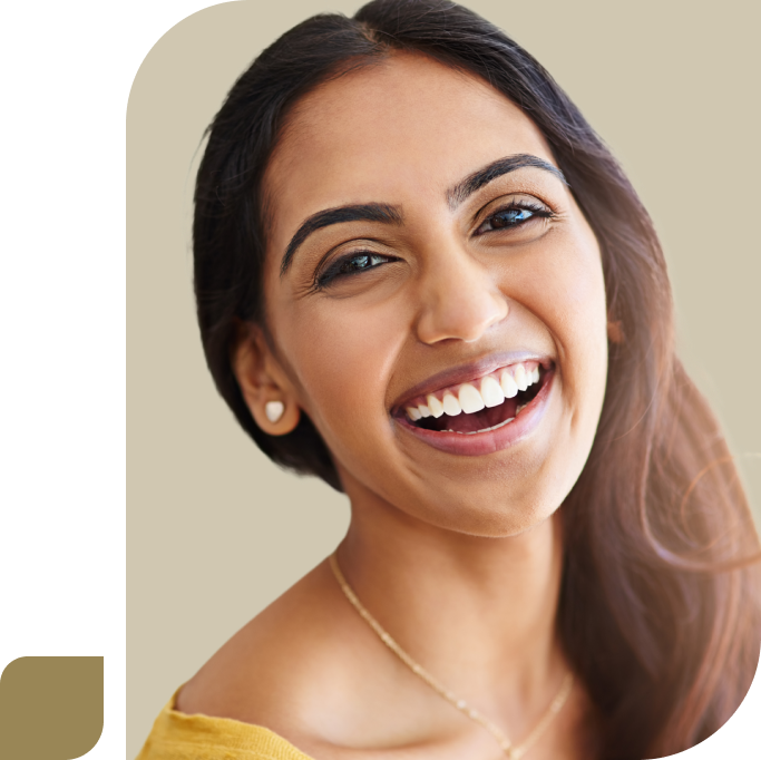 A woman with long hair and a nice smile is wearing a yellow top and earrings, looking at the camera.
