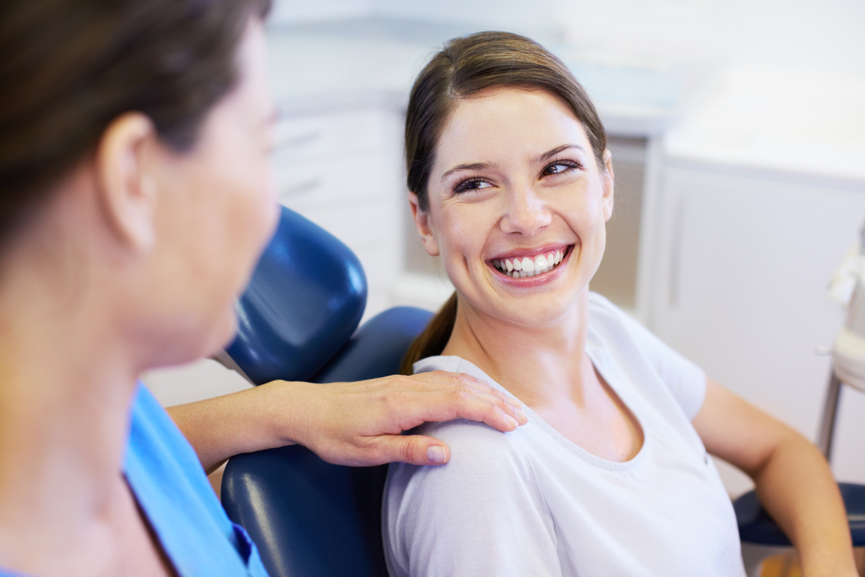 A pretty young woman smiling during a conversation with her friendly orthodontist