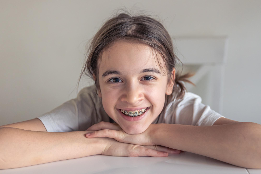 A teenage girl with braces, resting her head on a white table.